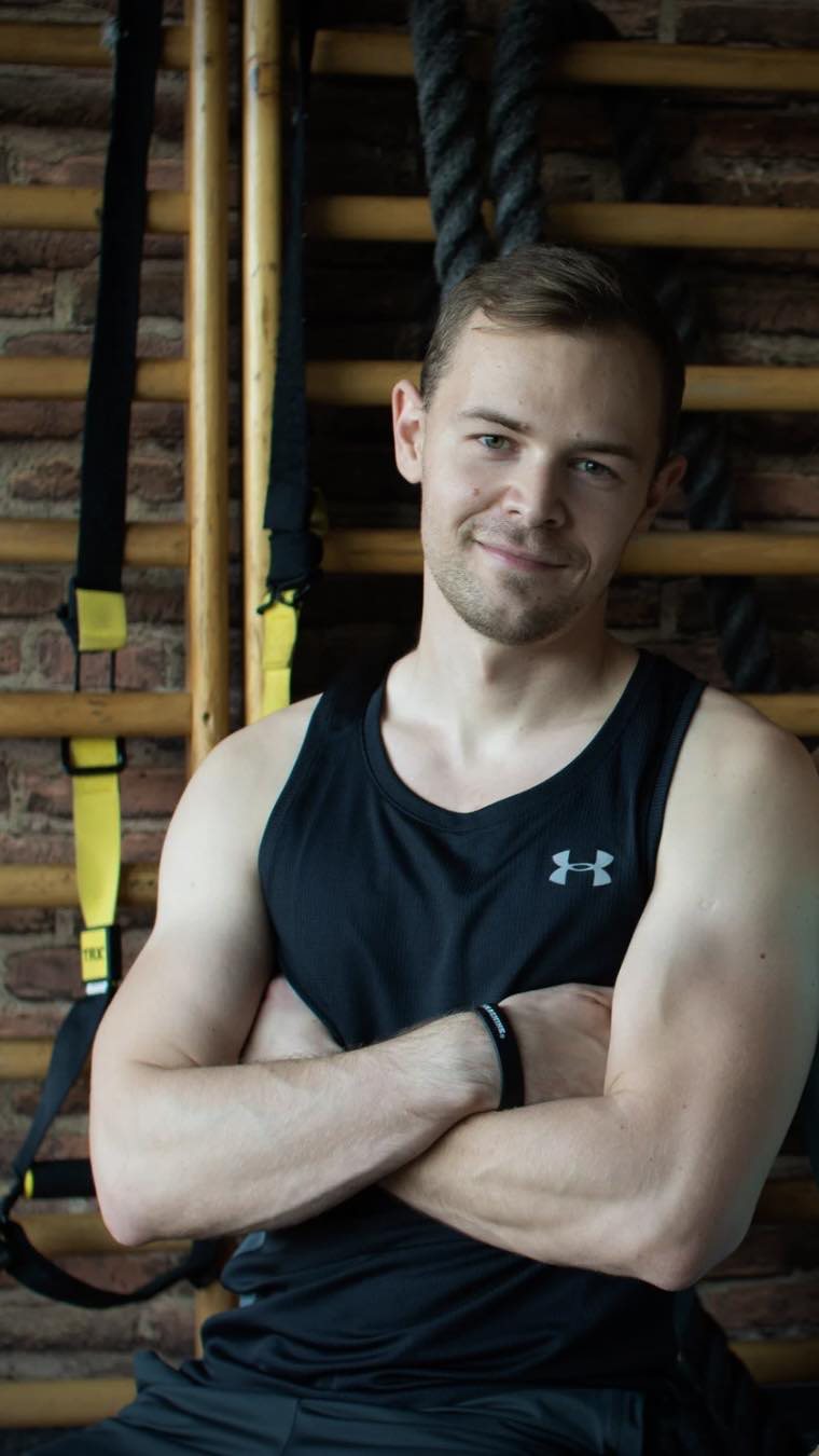 Tóth Máté karba tett kézzel a bordásfalnál, TRX-hevederek mellett